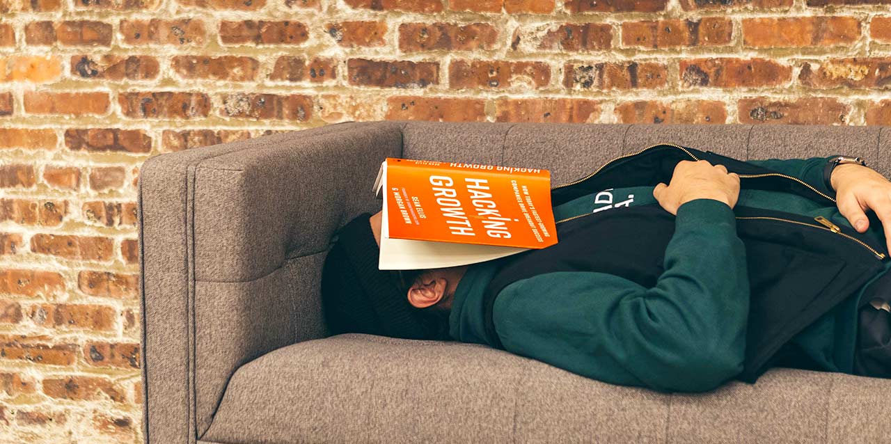 rapaz a dormir no sofá com livro na cara