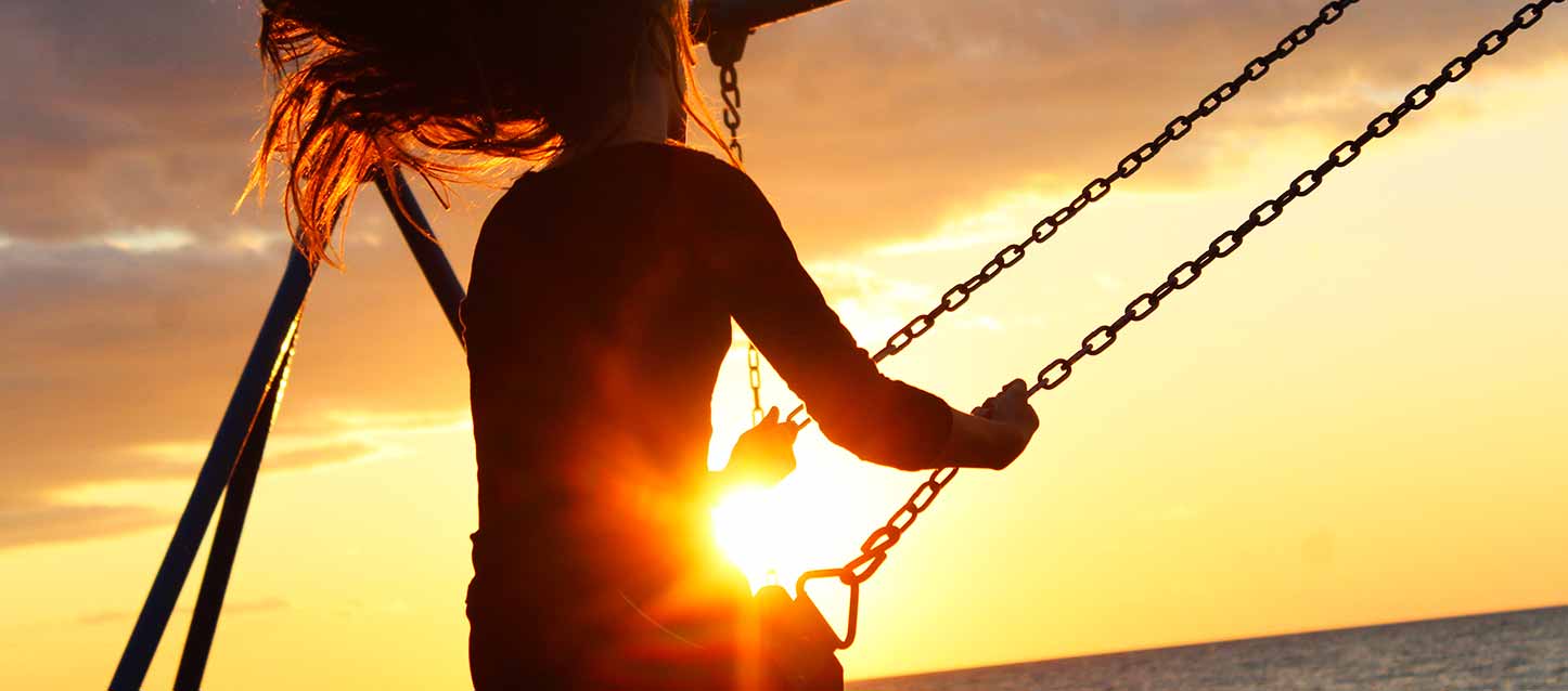 menina a baloiçar-se ao pôr do sol