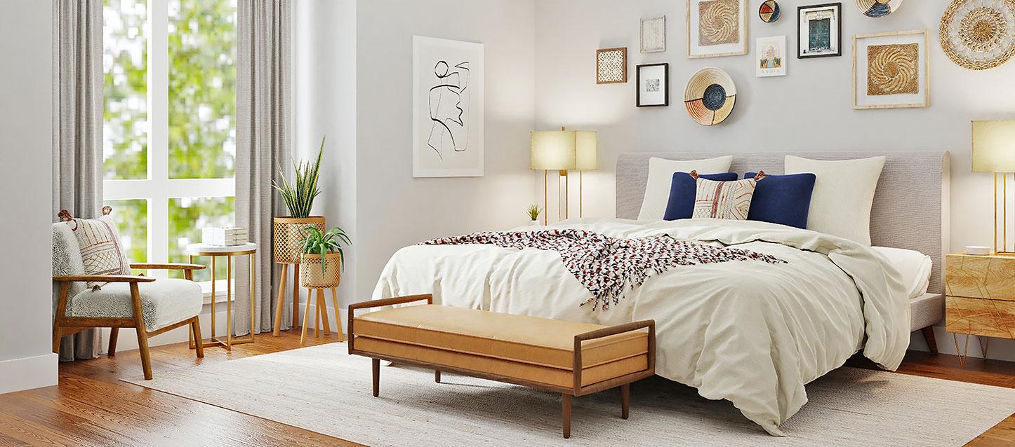 quarto com cama com base e cabeceira de cor bege, 3 travesseiros e 2 almofadas, e vários quadros decorativos na parede