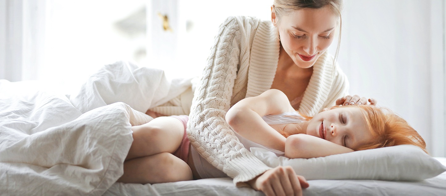 mãe a acariciar com ternura a sua filha, que está a dormir de lado