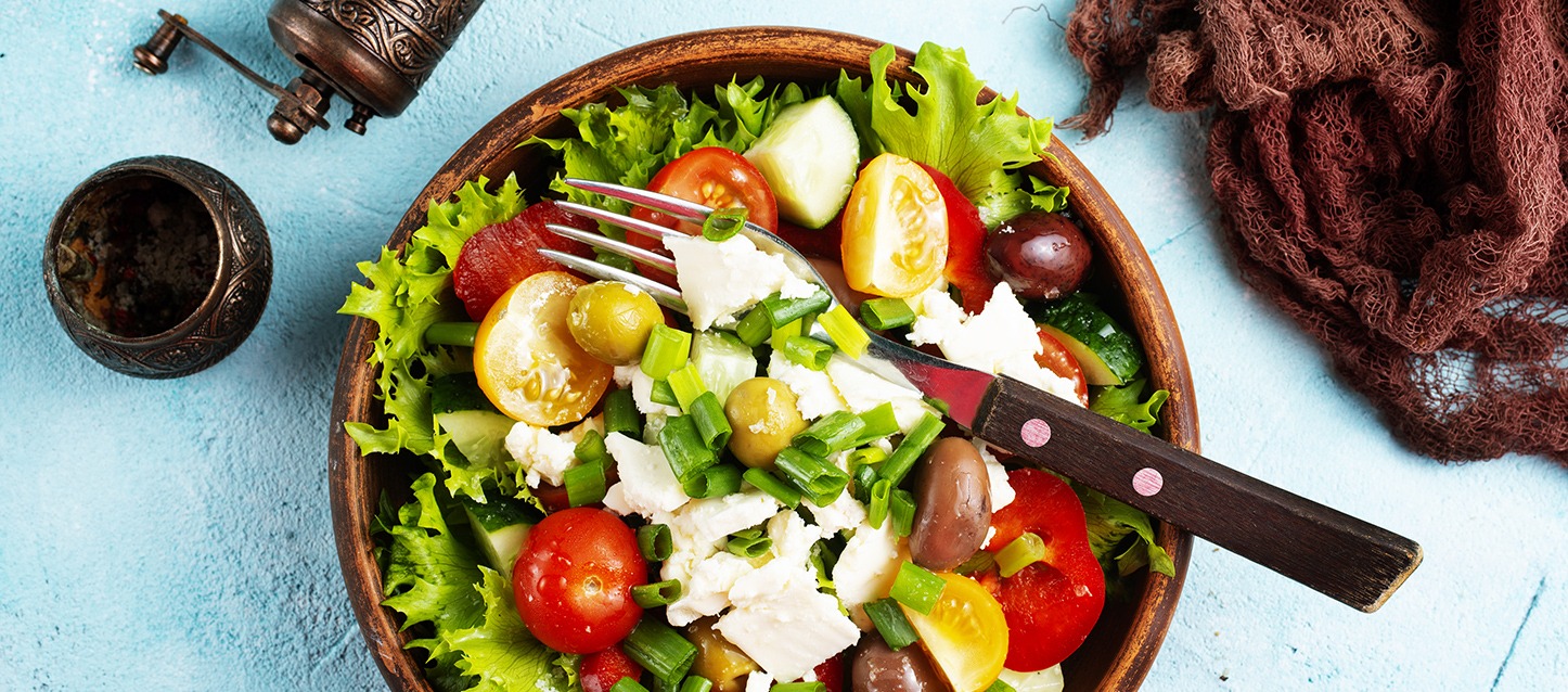 taça de madeira com salada de alface, tomate-cereja, azeitonas, pepino, ricotta e cebolinho