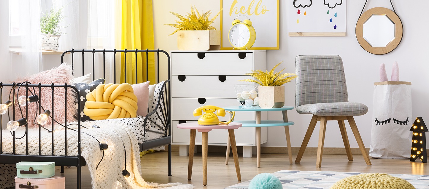 quarto infantil com cama, mesinha com telefone antigo amarelo, cadeira, armário com gavetas, e espelho na parede
