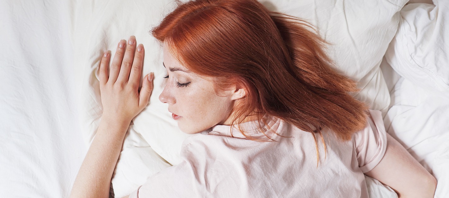 rapariga ruiva a dormir, com uma camisa rosa clara como pijama